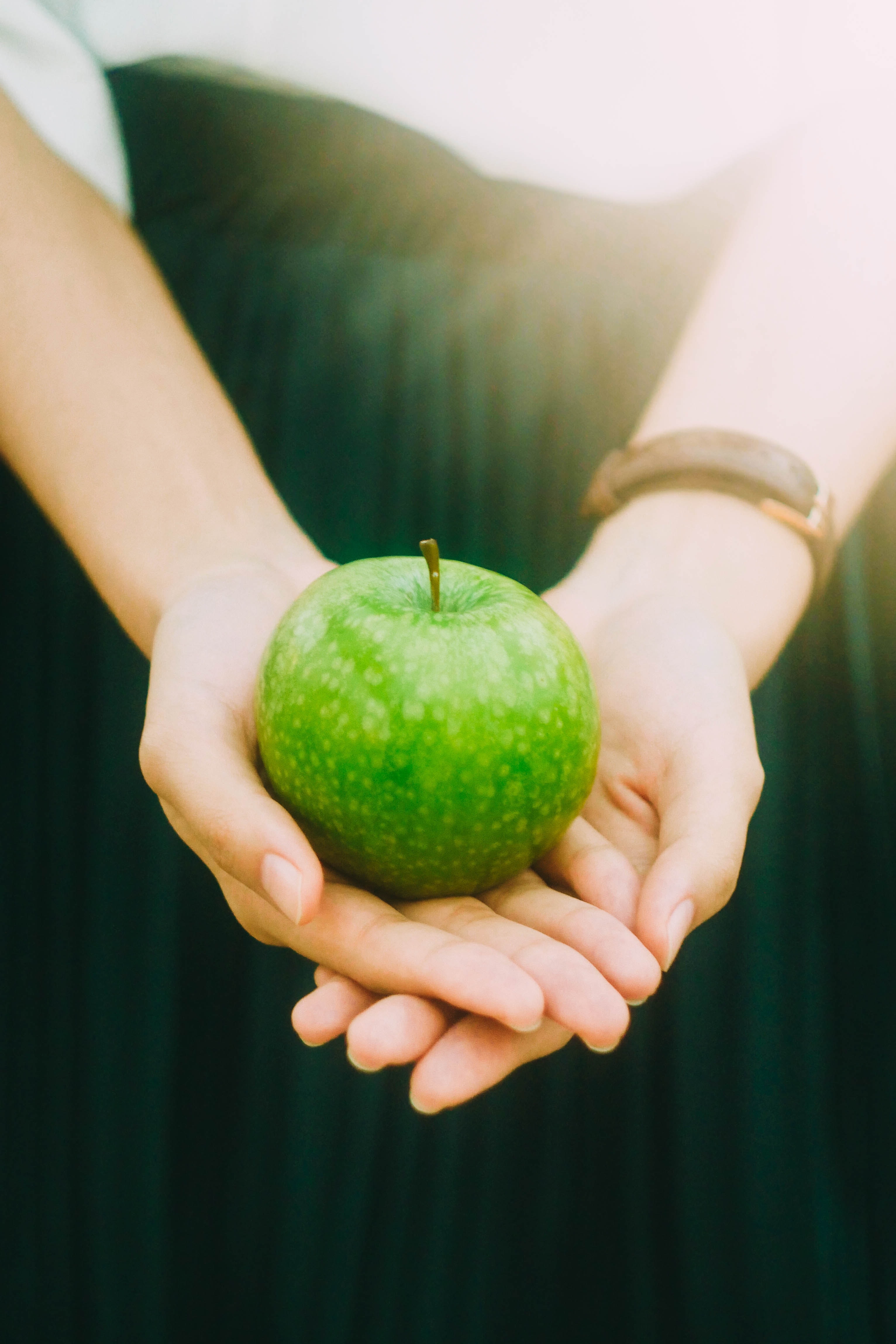 dłonie trzymające zielone jabłko