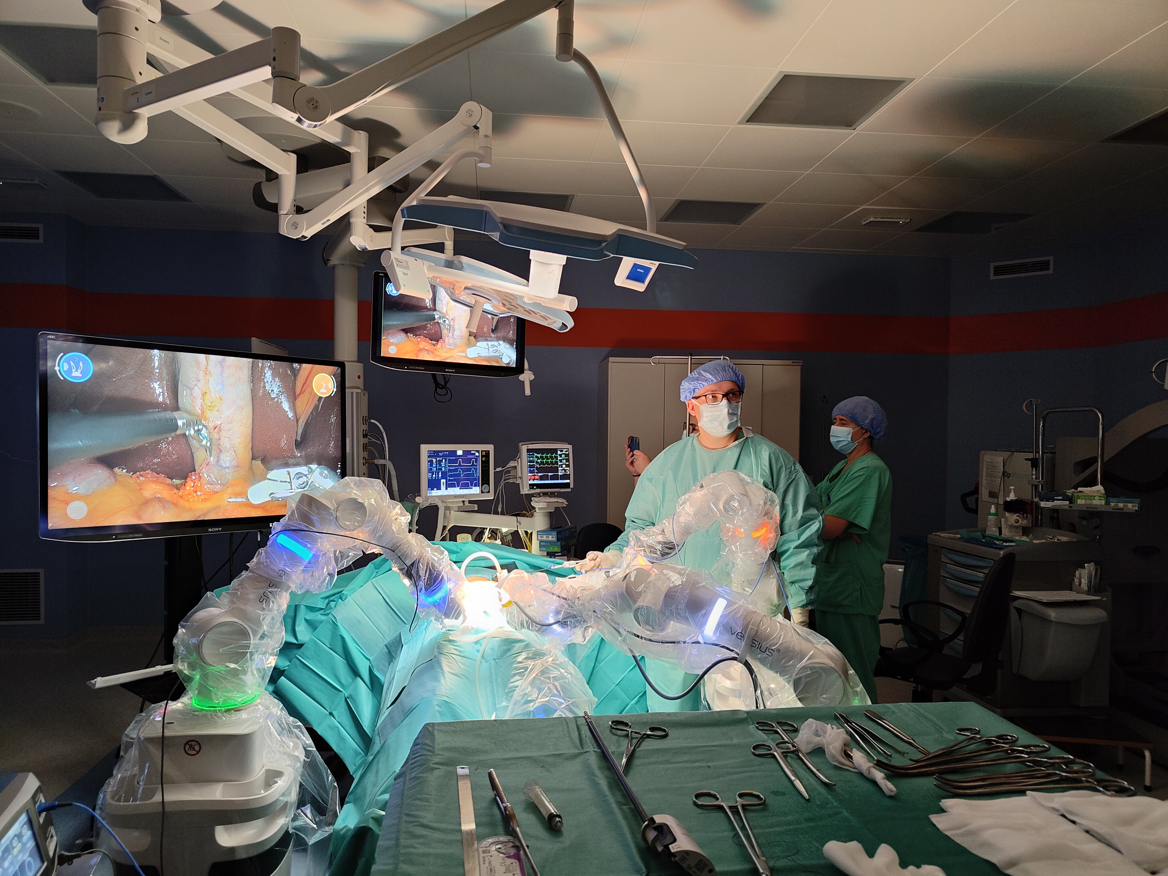 Lekarz na sali operacyjnej, pośród sprzętu, na stole operacyjnym leży operowany pacjent 
