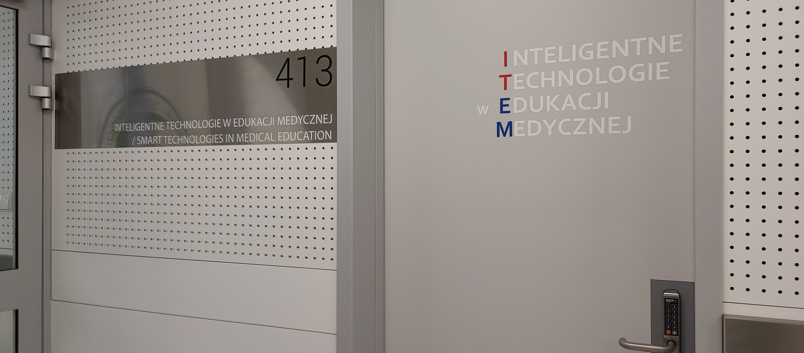 Zdjęcie przedstawia drzwi do pokoju 413 w Centrum Symulacji Medycznej. Pokój 413 jest siedzibą zespołu ITEM - Inteligentnych Technologii w Edukacji Medycznej.