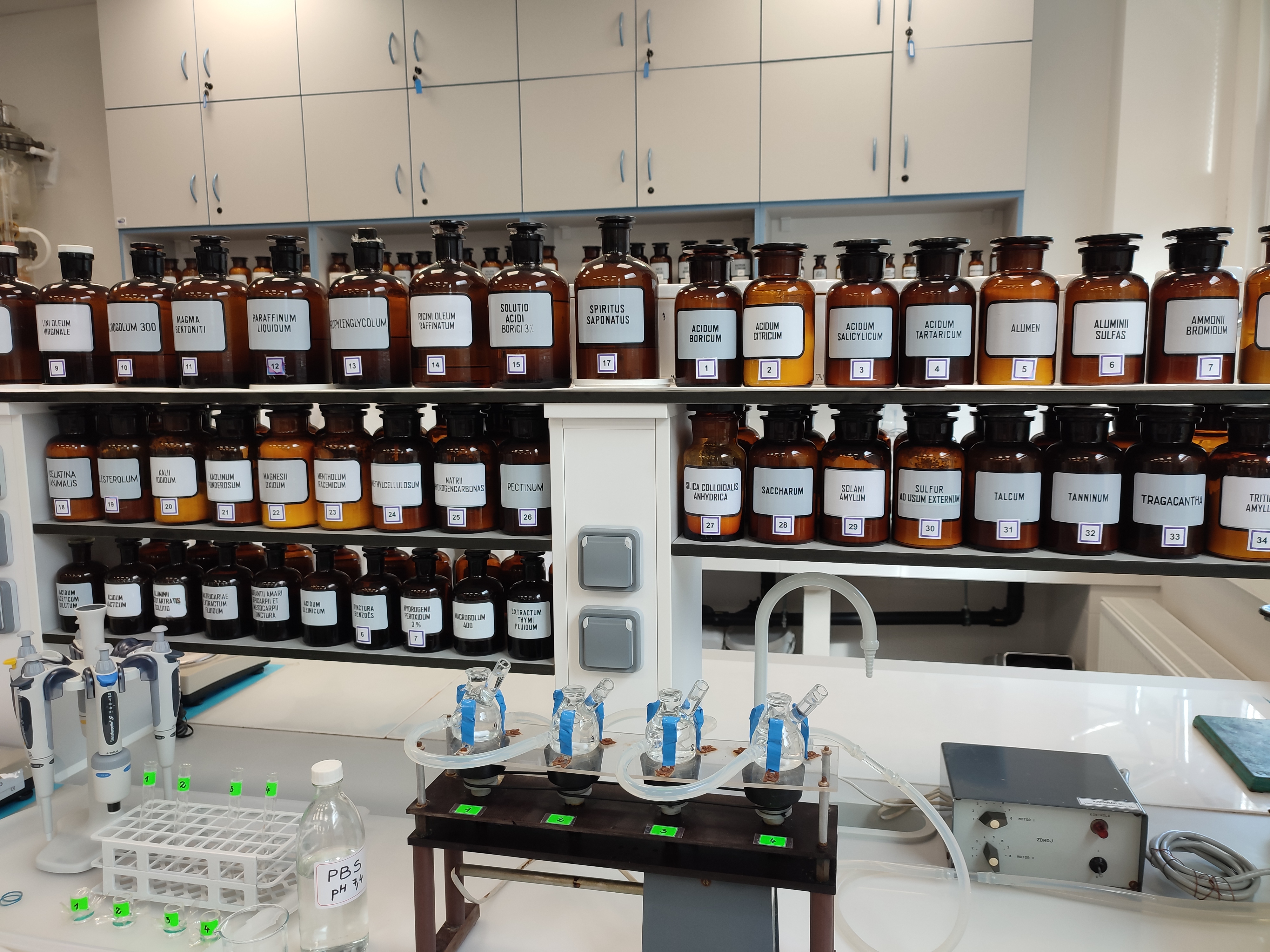 Na półkach w laboratorium farmaceutycznym stoją ciemne butelki z różnymi preparatami
