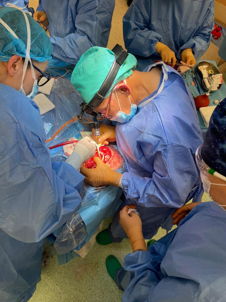 Zdjęcie z sali operacyjnej, lekarze pochyleni nad polem operacyjnym