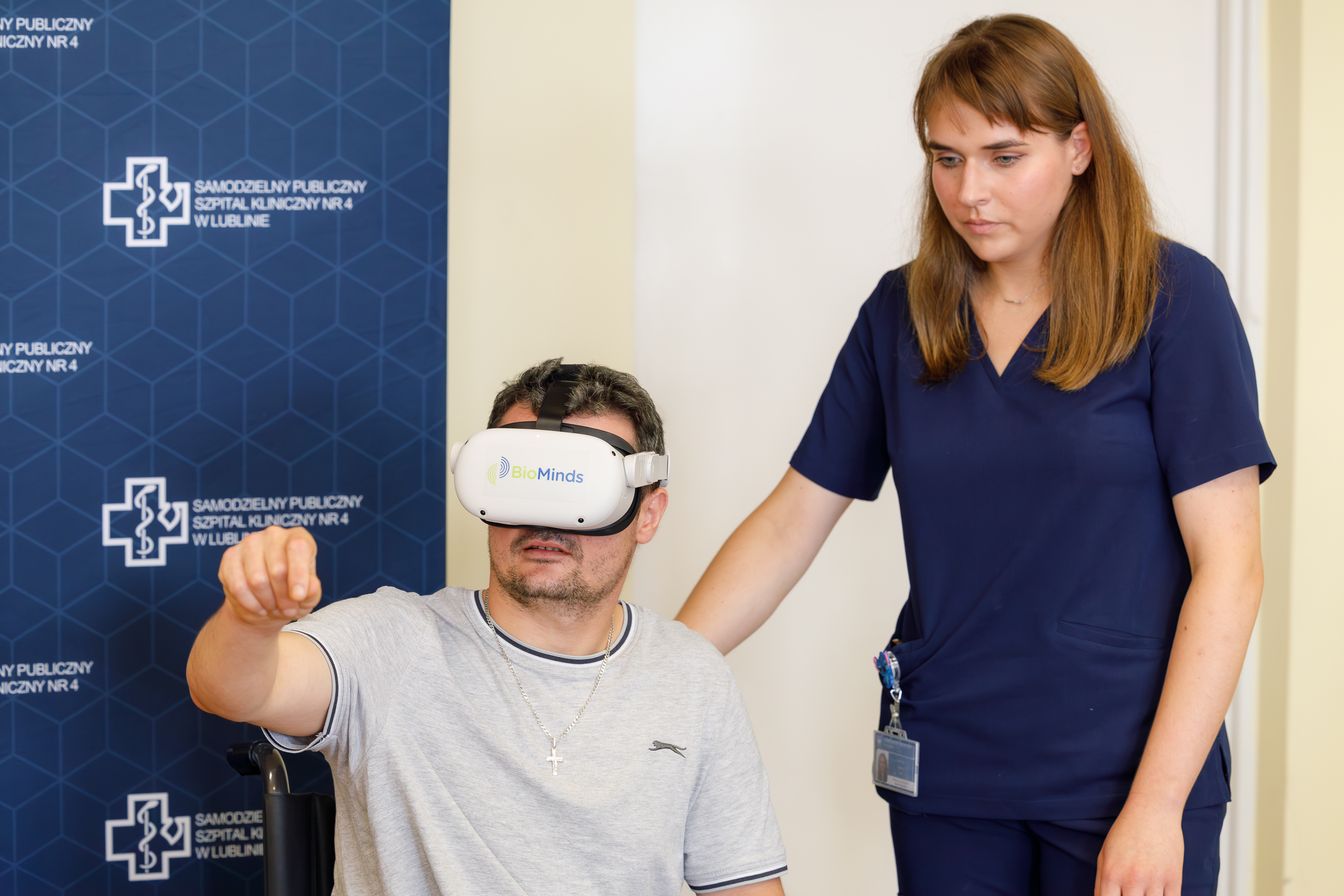Pacjent na wózku używa okularów VR w celu rehabilitacji, obok stoi lekarka