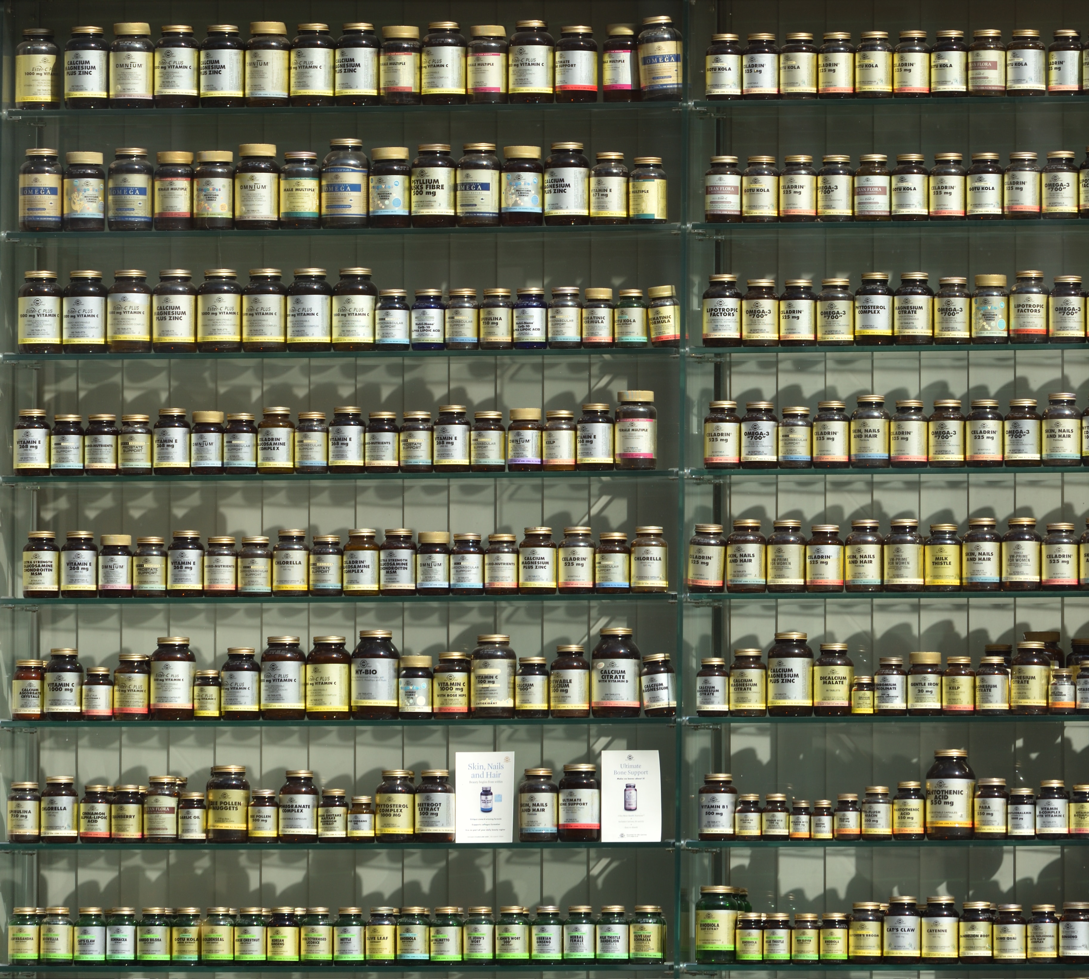 Zdjęcie ilustracyjne z platformy unsplash.com. Przedstawia regał, na półkach ustawione są różnej wielkości słoiczki z lekami