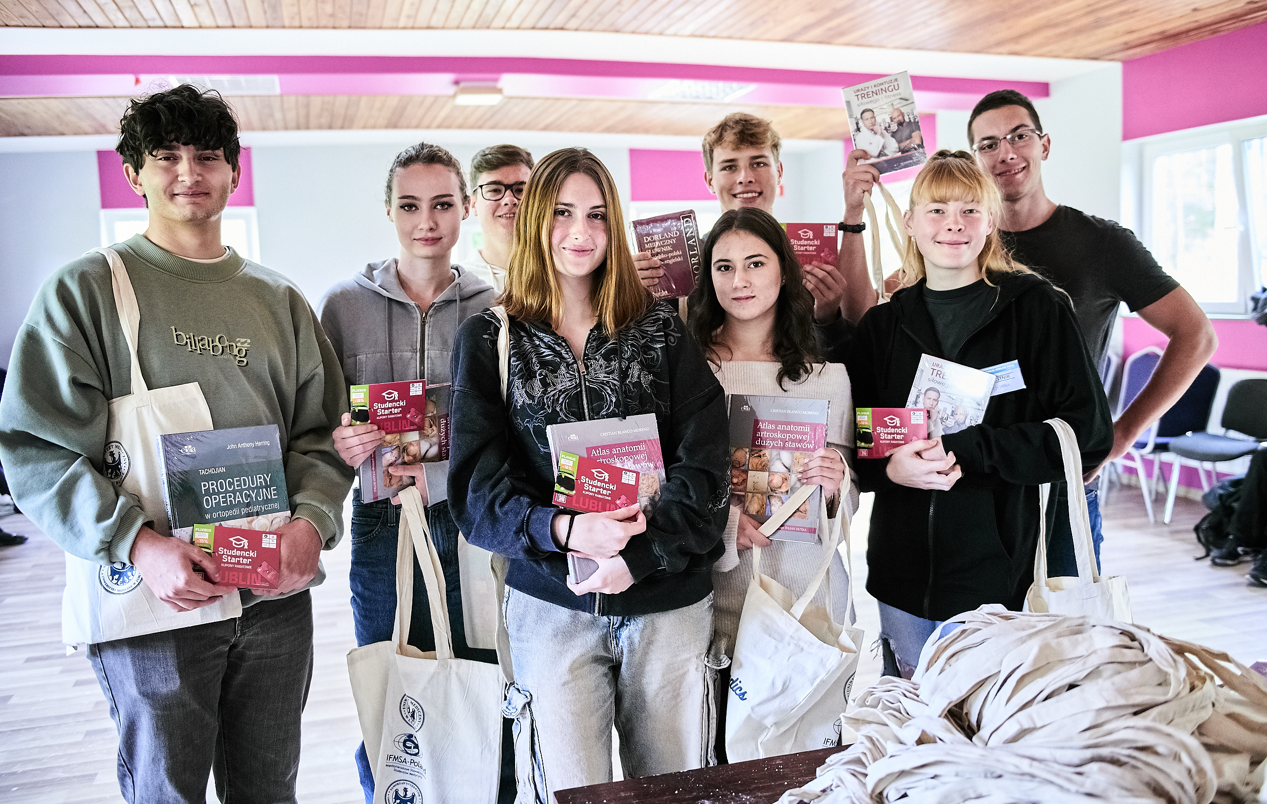 grupa studentów pozycje z pomocami studenciego startera, to jest podręcznikami i torbami uniwersyteckimi