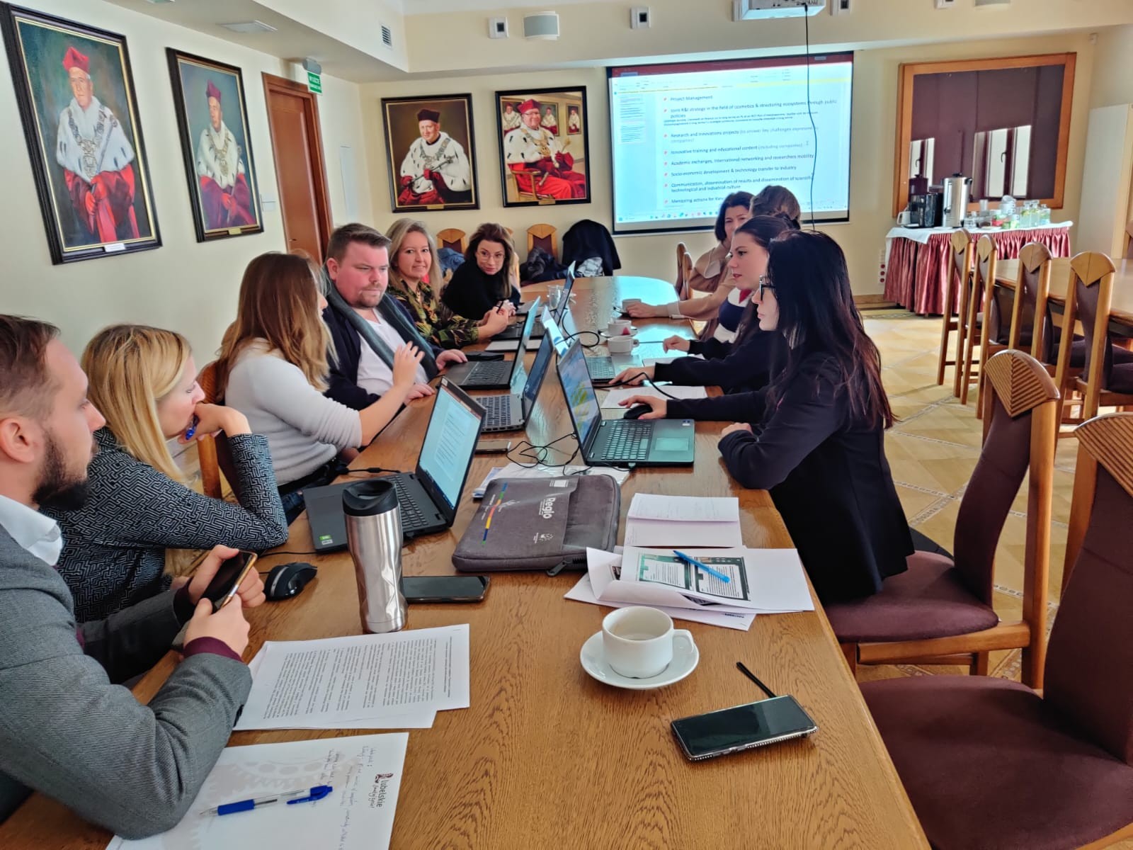 Spotkanie projektowe członków platformy Go4Cosmetics - uczestnicy obradują przy stole konferencyjnym, piszą na laptopach