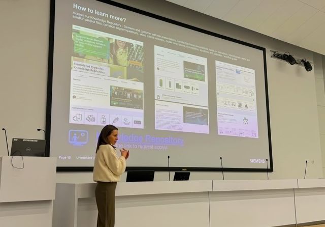 prezentacja firmy Siemens - kobieta mówi do mikrofonu a w tle wyświetlana jest treść prezentacji jako slajd