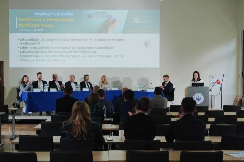 grupa osób na scenie za stołem prezydialnym